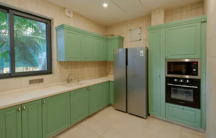 Modern kitchen with cabinets and built-in appliances such as a fridge, microwave, and oven at Lime Tree Villa with Private Pool | Luxury Stay in Goa.